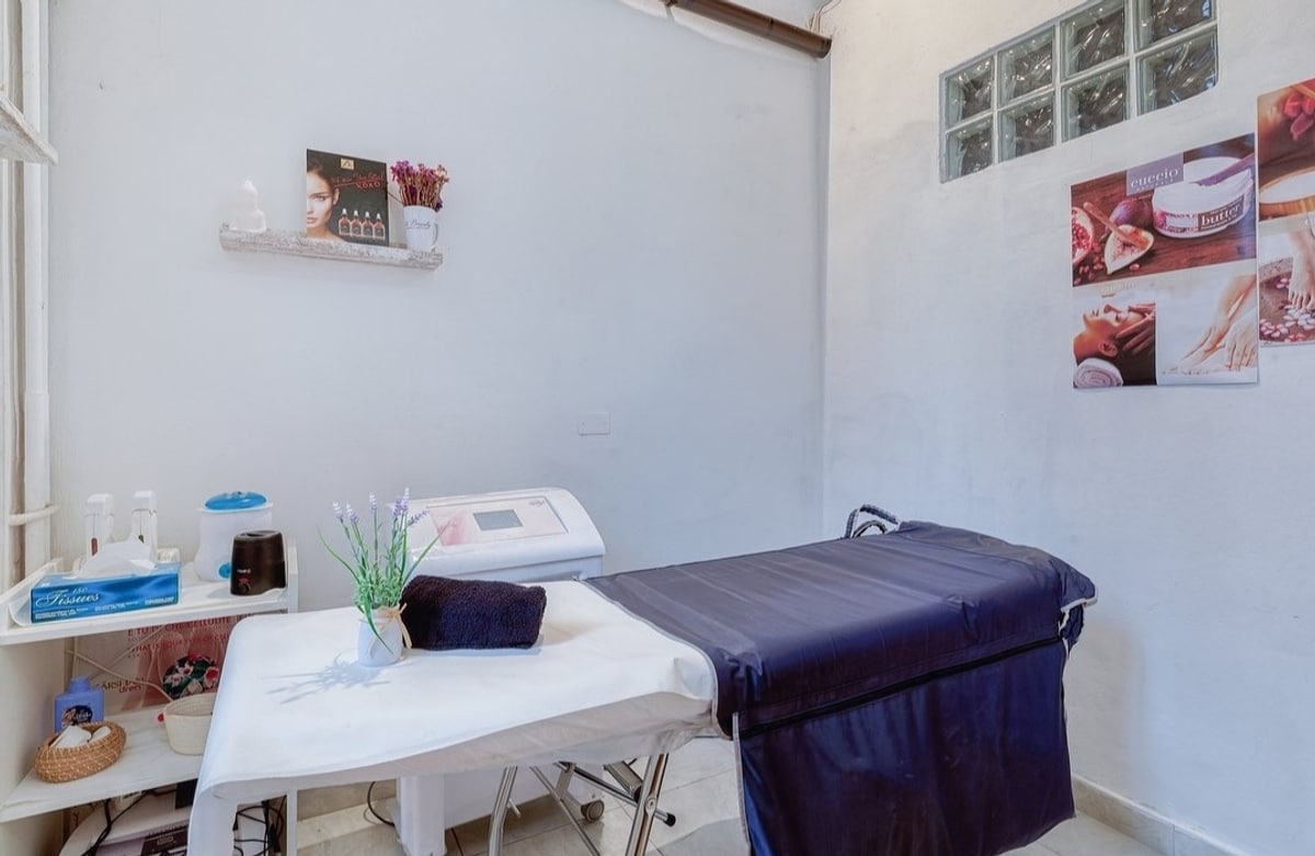 Una cabina trattamenti con il lettino, l'apparecchiatura e i poster dei servizi