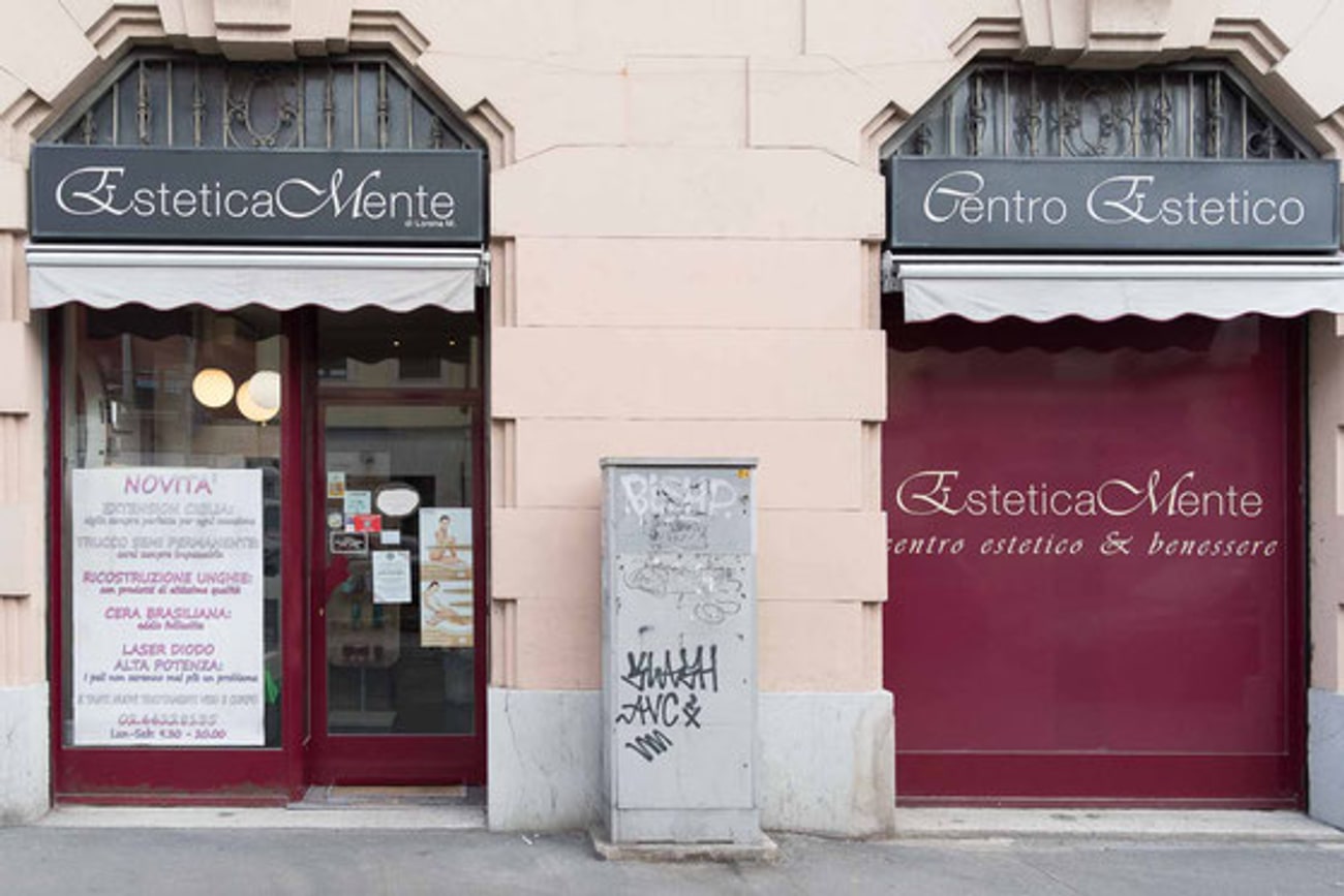 La facciata di EsteticaMente in Via Astesani, con l'insegna e il listino dei trattamenti sul vetro