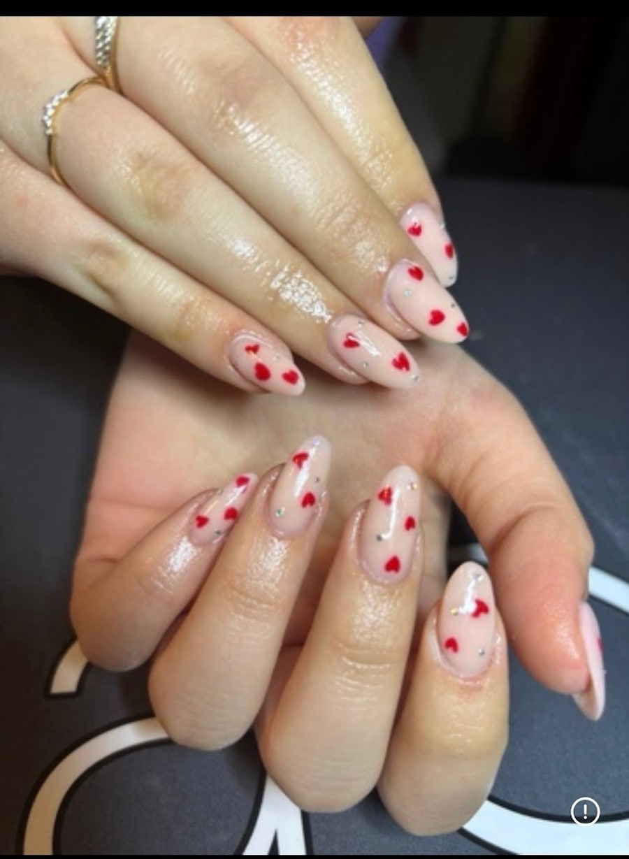 Nail art con cuoricini rossi su unghie a mandorla
