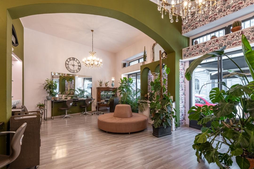 Interno di Estilò: arco verde, salottino terracotta e monstera
