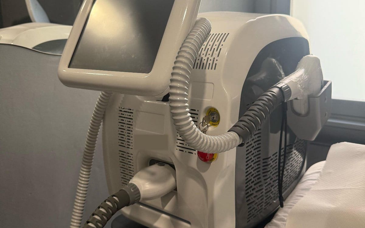 Il laser, bianco, col suo schermo e il manipolo, accanto al lettino.