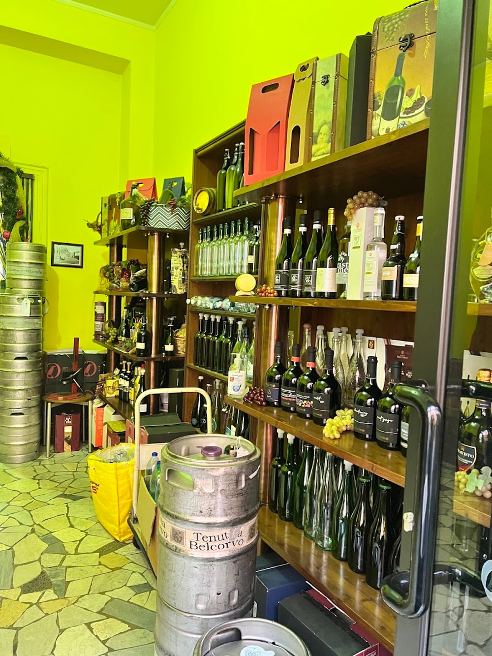 L'interno con le pareti verde acido, i fusti d'acciaio impilati e le bottiglie vuote in fila
