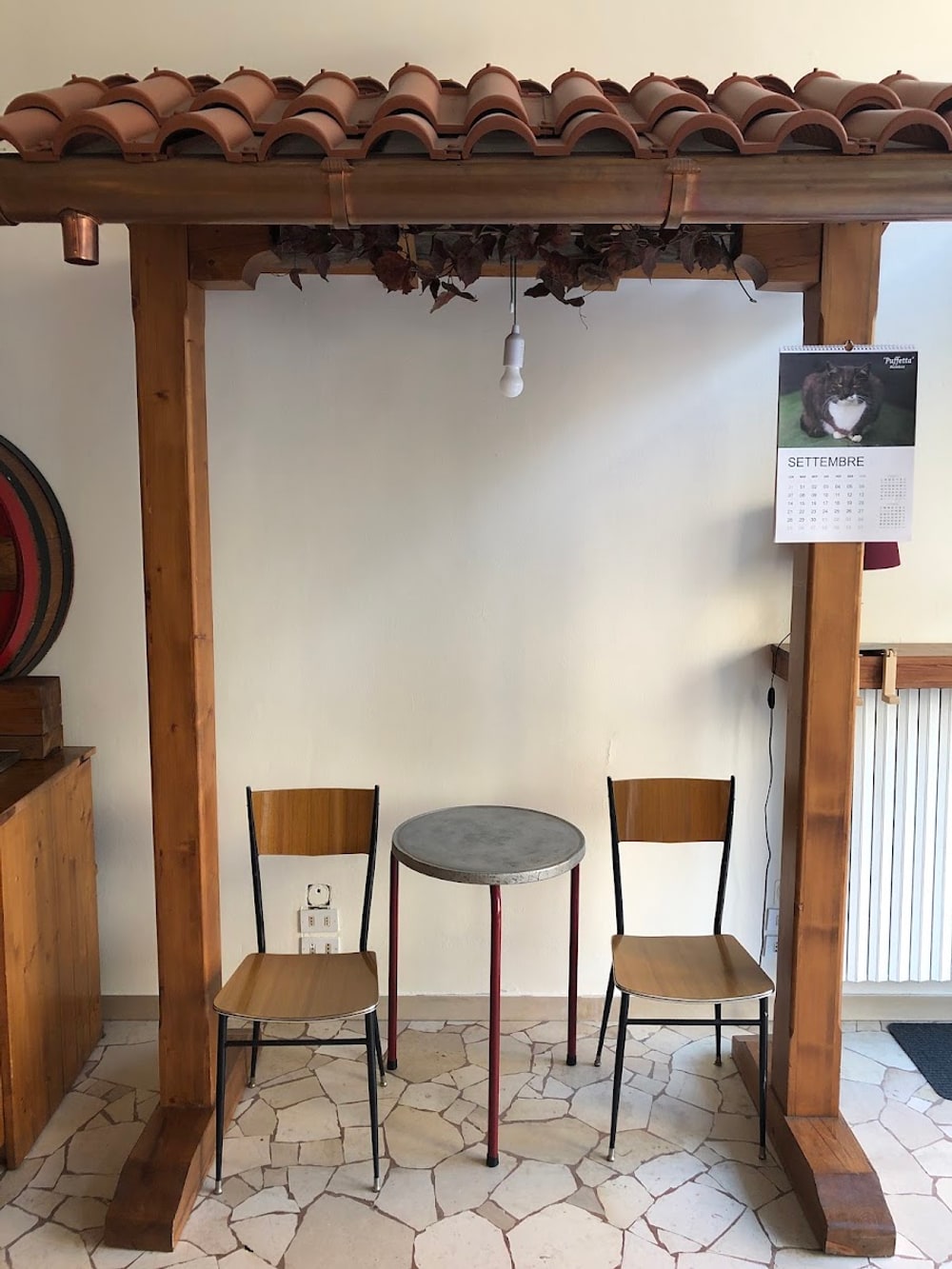 Il portico costruito dentro il negozio, con i coppi di terracotta e il tavolino con due sedie