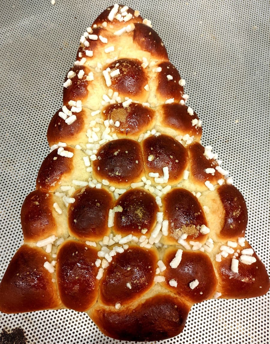 Un albero di Natale di pan brioche lucido, fatto di palline, con la granella di zucchero.