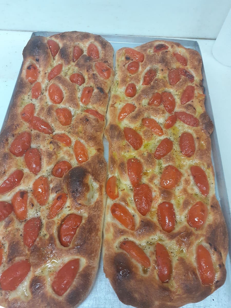 Le stesse due focacce cotte, dorate, coperte di pomodorini.