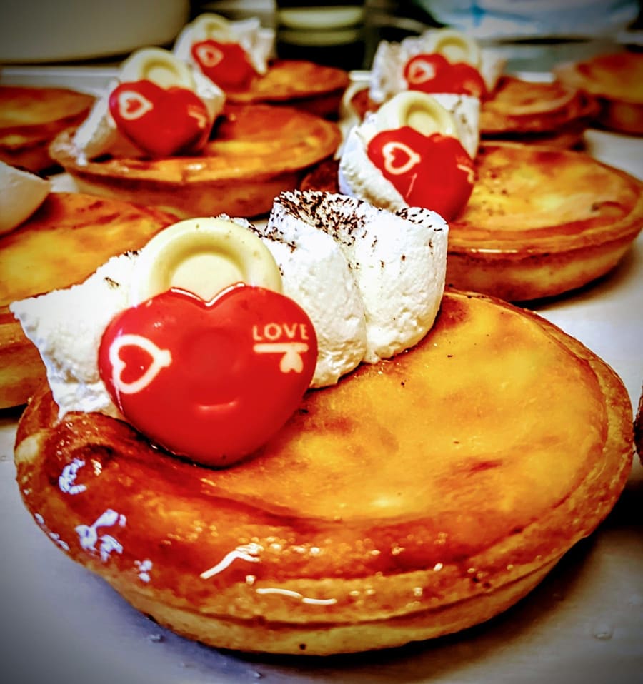 Crostatine dorate con un cuore rosso di cioccolato e la panna.