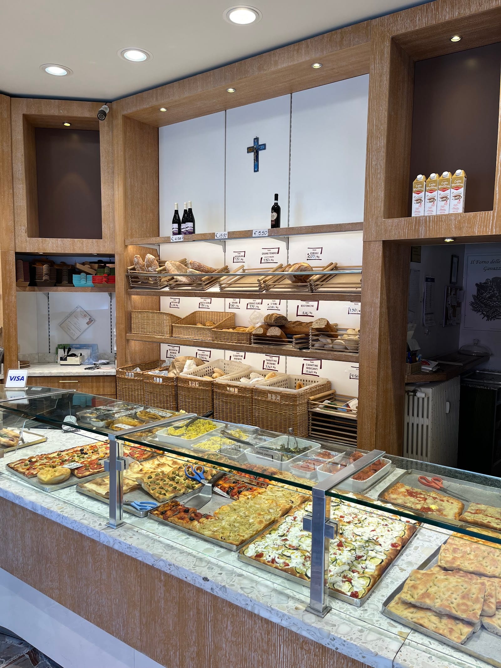 Il banco del Forno delle Fantasie: pizze e focacce al taglio davanti al muro del pane