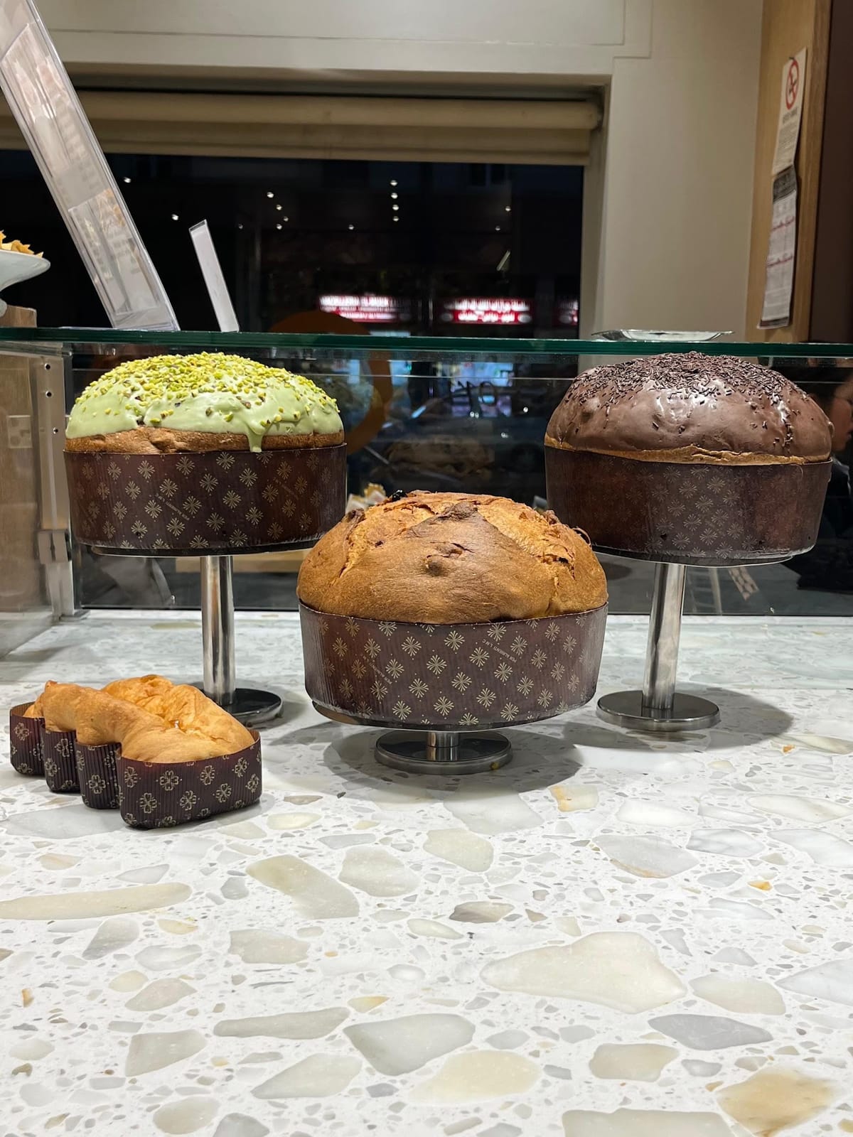 Tre panettoni artigianali sui trespoli: pistacchio, classico e cioccolato