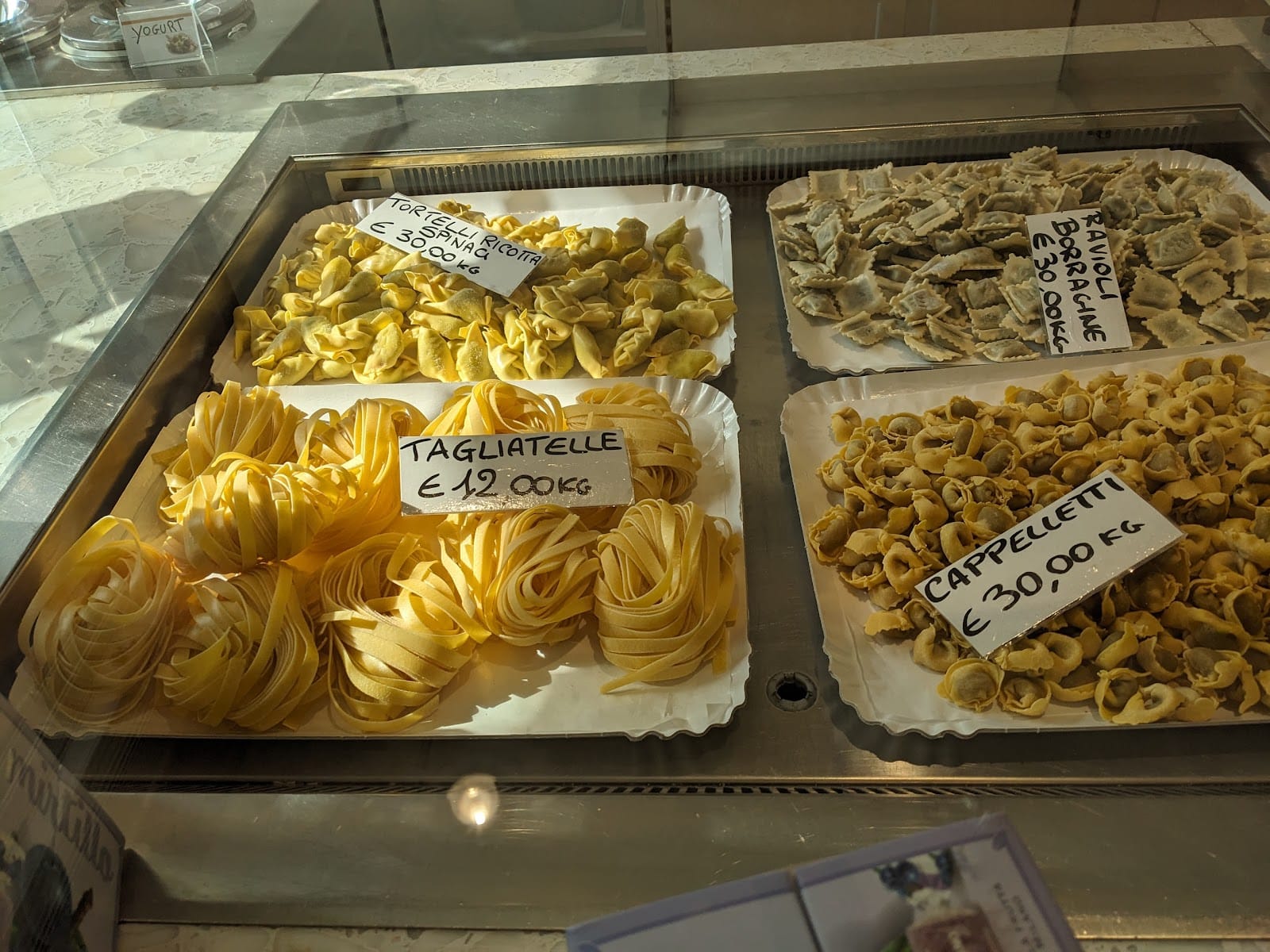 La vetrina della pasta fresca: tagliatelle, tortelli, cappelletti e ravioli coi cartellini scritti a mano