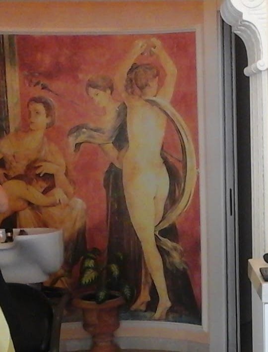 L'affresco in stile pompeiano: due danzatrici sul fondo rosso, accanto a una colonna ionica in stucco.