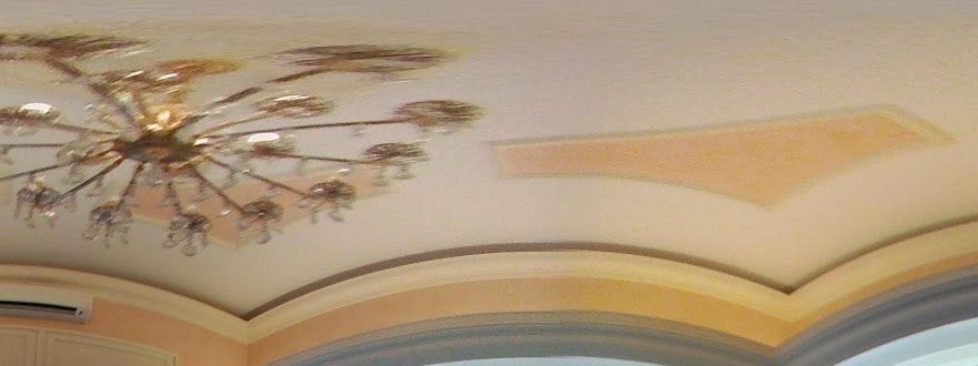 Il soffitto a riquadri dipinti color pesca e il lampadario di cristallo.