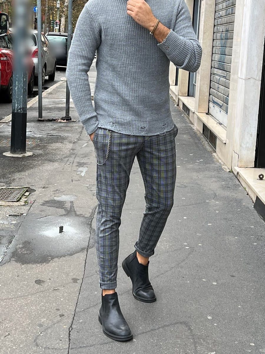 Look 06: dolcevita grigio a coste, pantalone a quadri con la catenella e chelsea boot neri, sul marciapiede