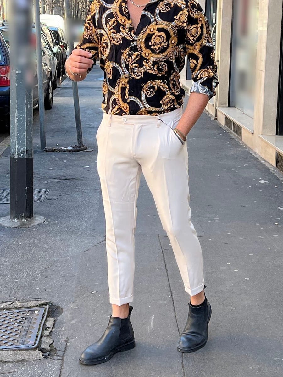 Look 09: camicia con la stampa barocca nero e oro, pantalone bianco e chelsea boot neri, sul marciapiede