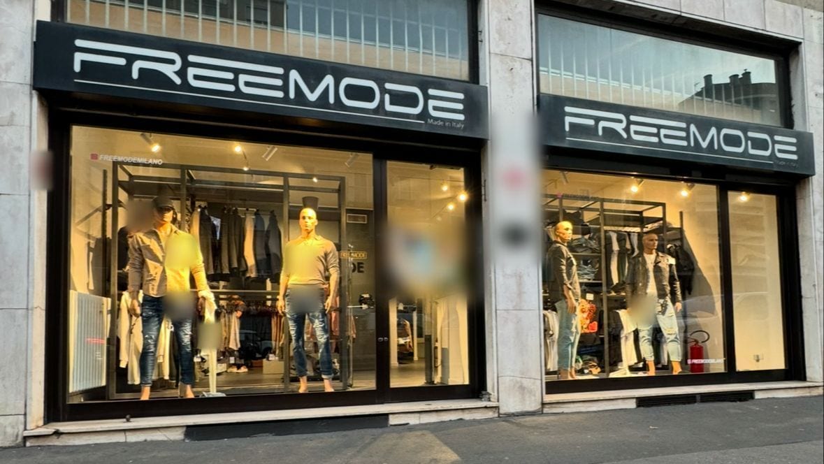L'insegna FREEMODE nera con le lettere bianche sopra le due vetrine, di giorno