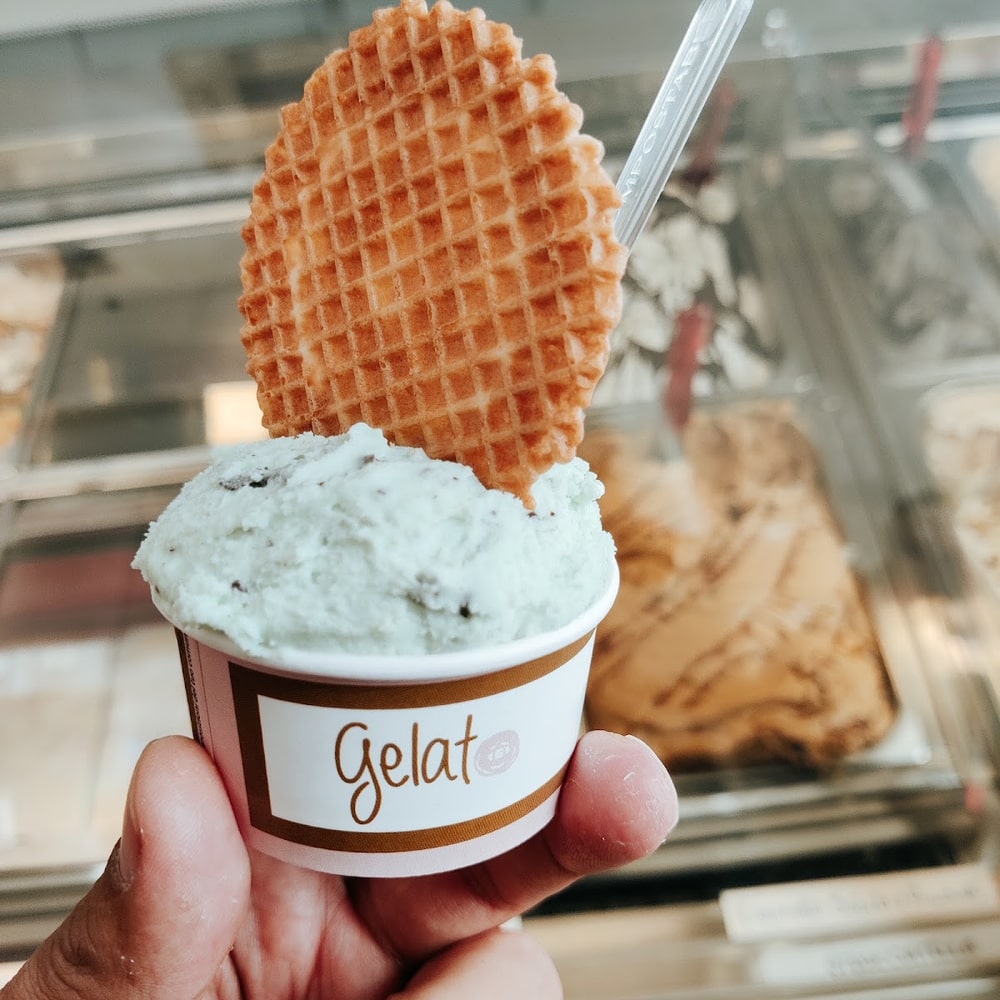 Una coppetta di gelato menta e stracciatella con la cialda a nido d'ape, davanti al banco