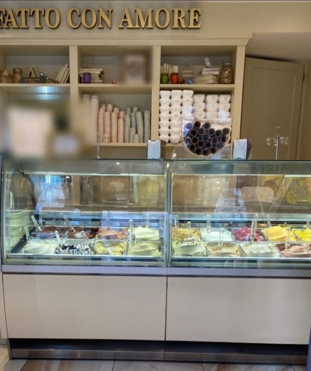 La scritta dorata, le mensole color crema con le coppette e il bancone dei gusti.