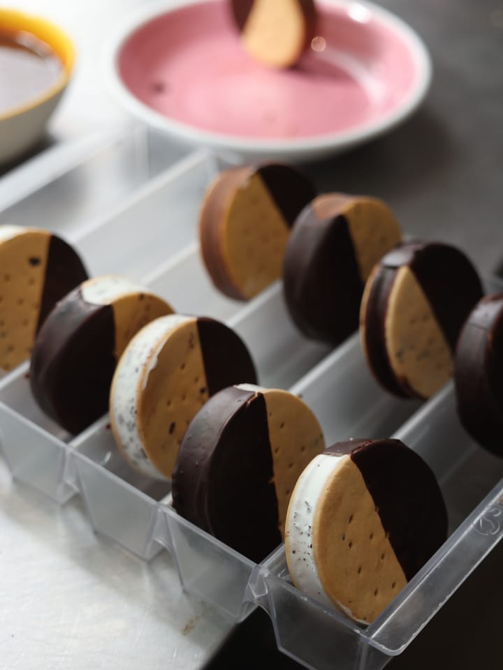 I biscotti gelato ricoperti a metà di cioccolato, in fila nella vaschetta.