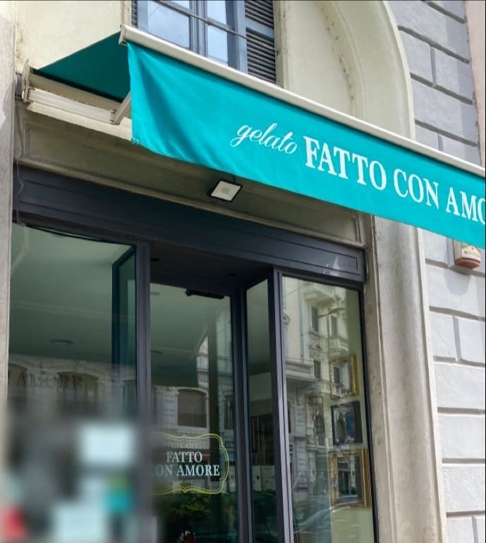 La tenda verde acqua «gelato FATTO CON AMORE» e la porta a vetri col loro logo dorato.