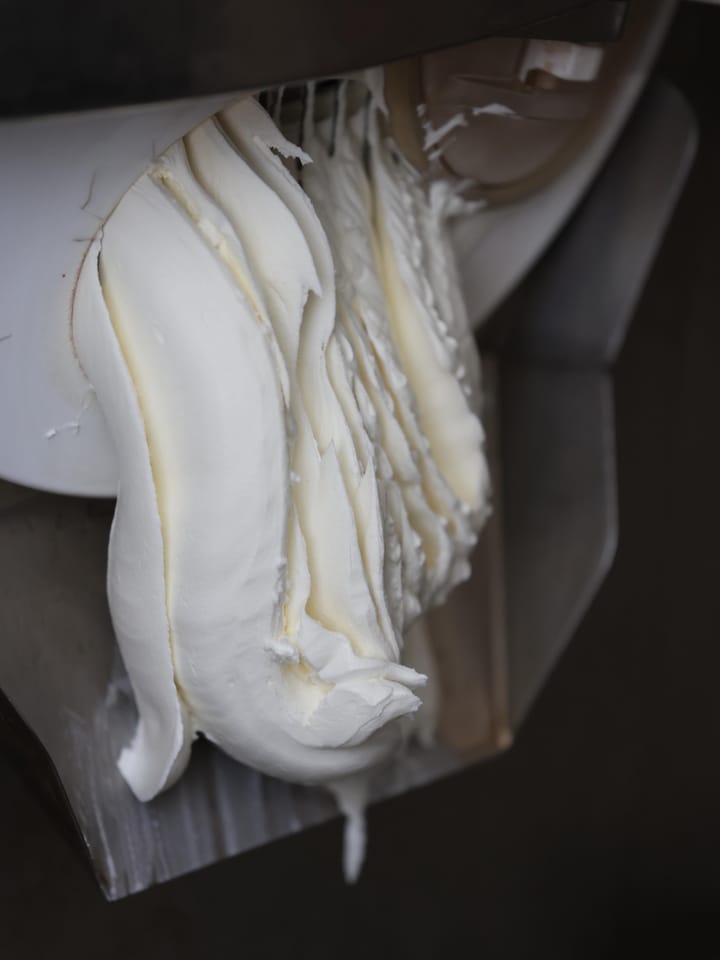 Lo yogurt greco che esce a nastro dalla mantecatrice.
