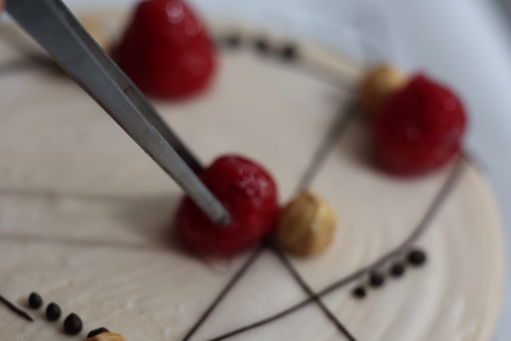 Le fragole appoggiate con la pinzetta sulla torta gelato.