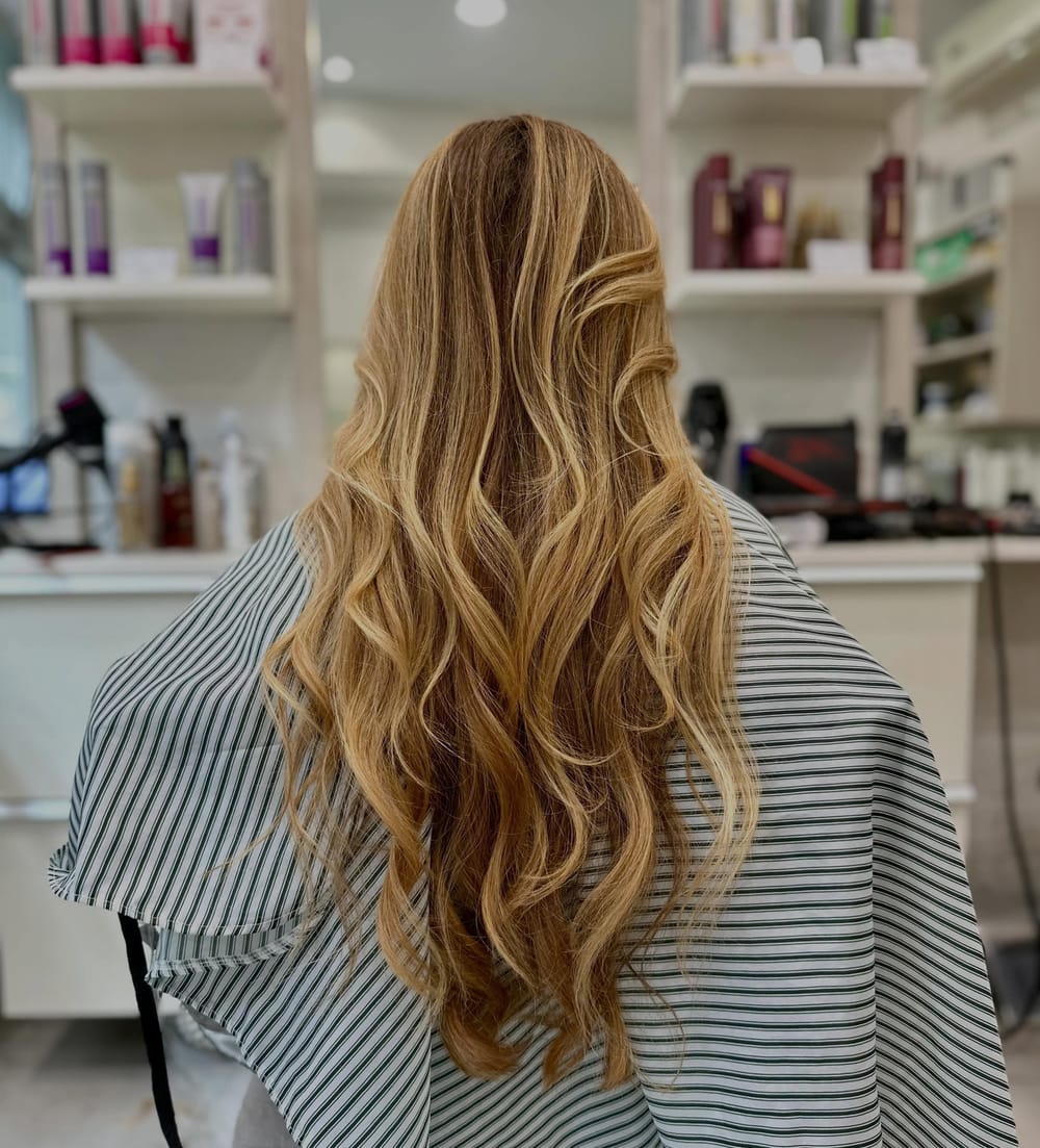Un balayage miele a onde lunghe, di spalle, con la mantellina a righe verdi e bianche.