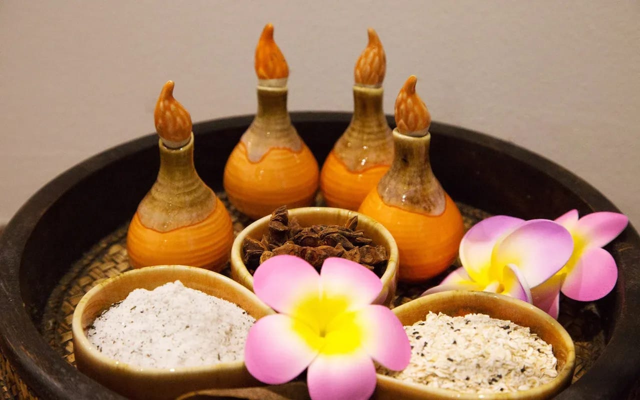 Le ampolle d'argilla col tappo a fiamma sul vassoio, le ciotole di sale, i frangipani.