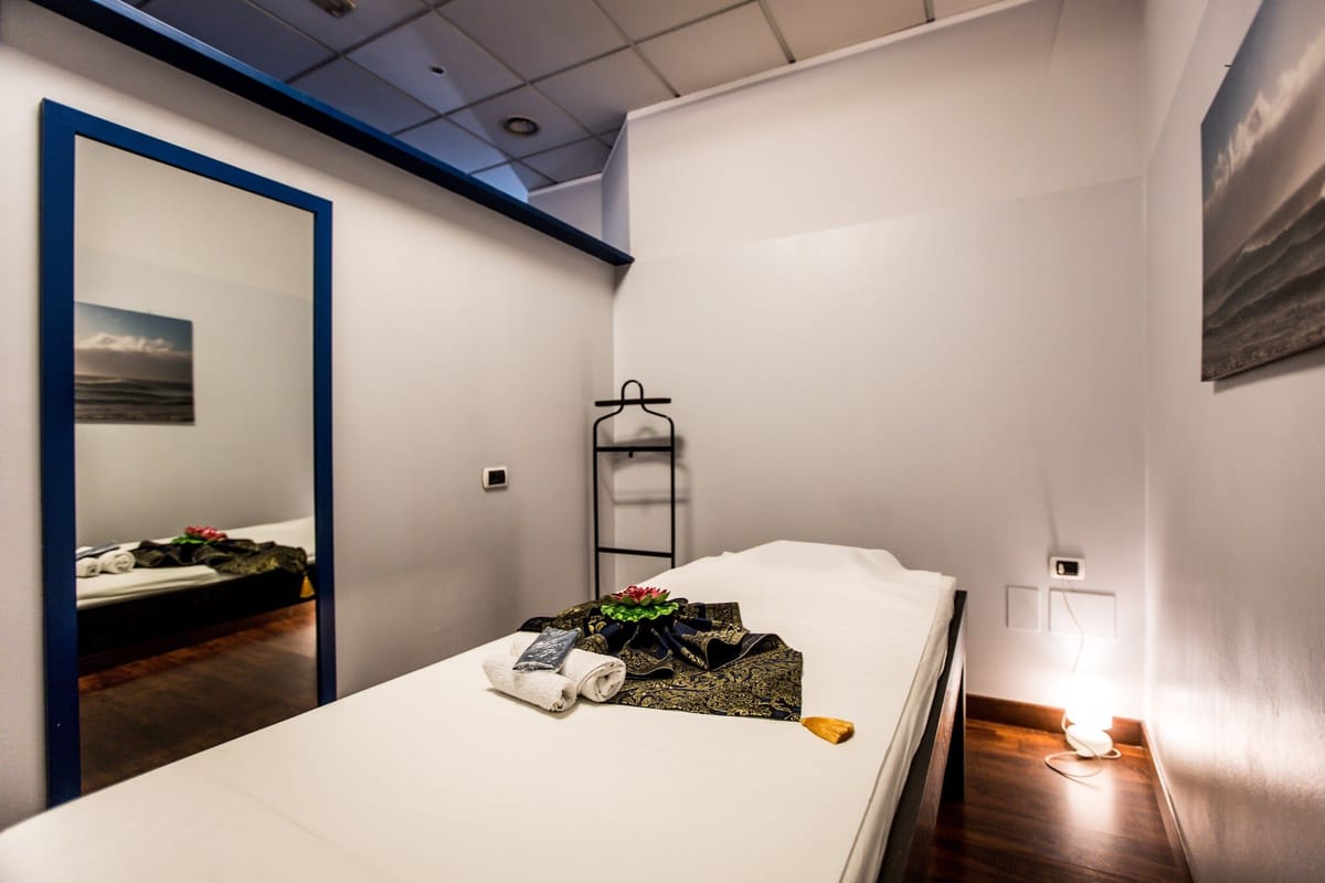 Una cabina bianca con lo specchio nella cornice blu e il lettino.