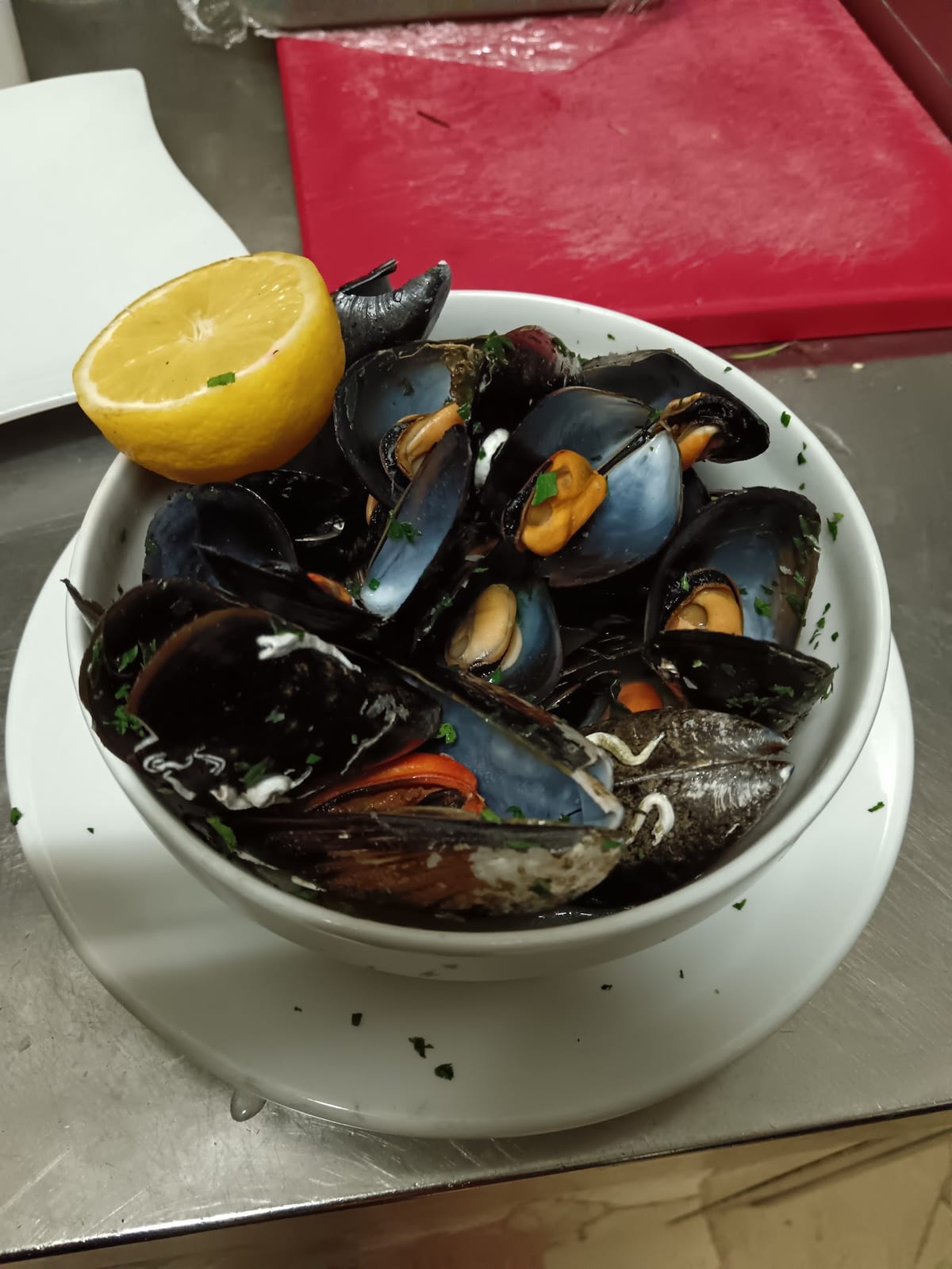 Sautè di cozze in ciotola bianca con mezzo limone
