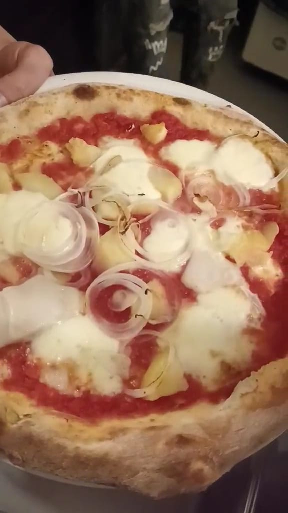 Pizza tonda dal cornicione alto servita su piatto bianco