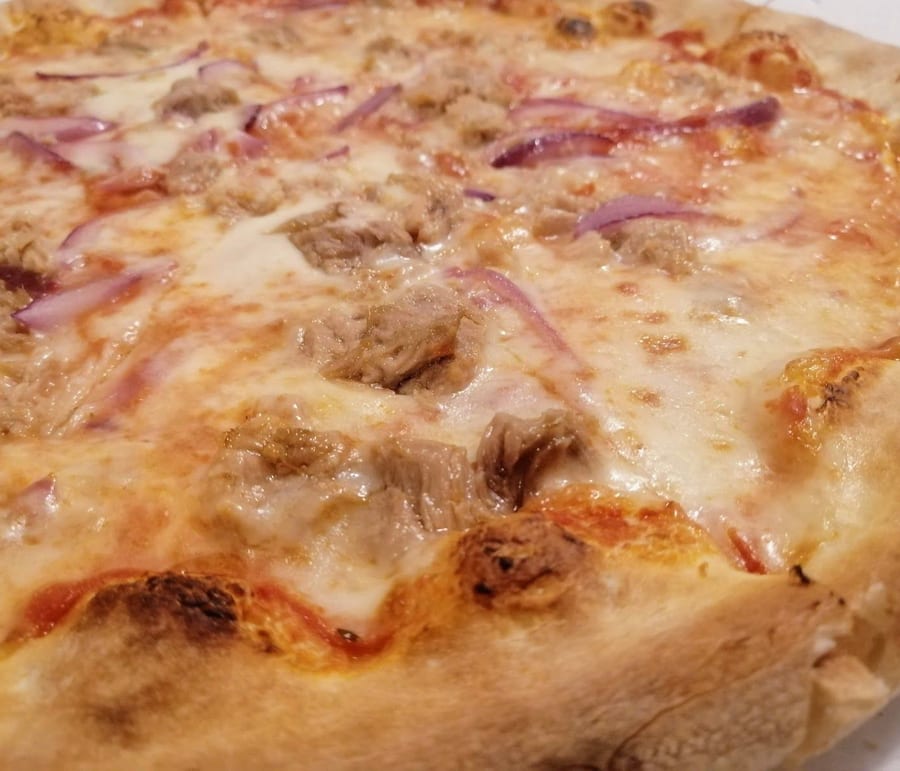 Una pizza tonno e cipolla rossa vista da vicino, col cornicione dorato.