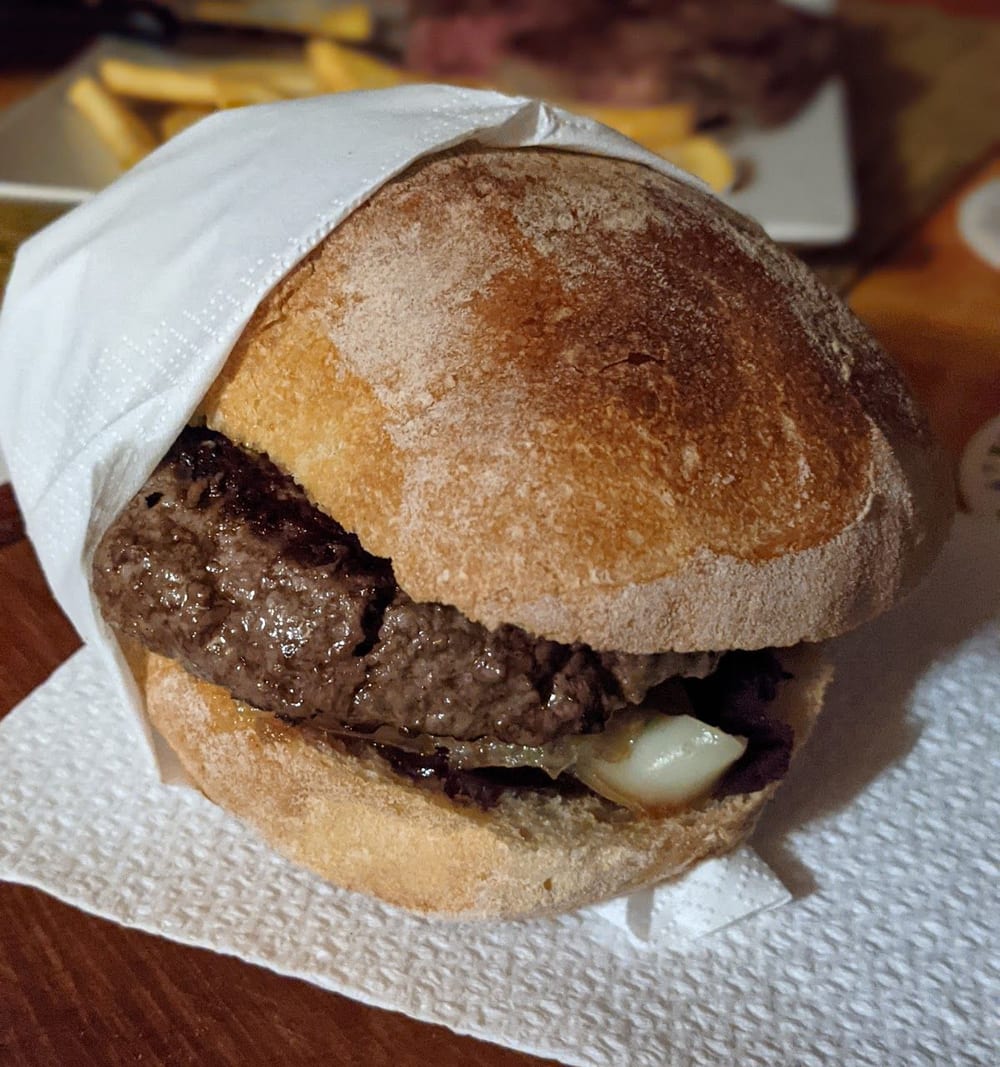 Un panino hamburger col pane di forno e il formaggio fuso, nella carta