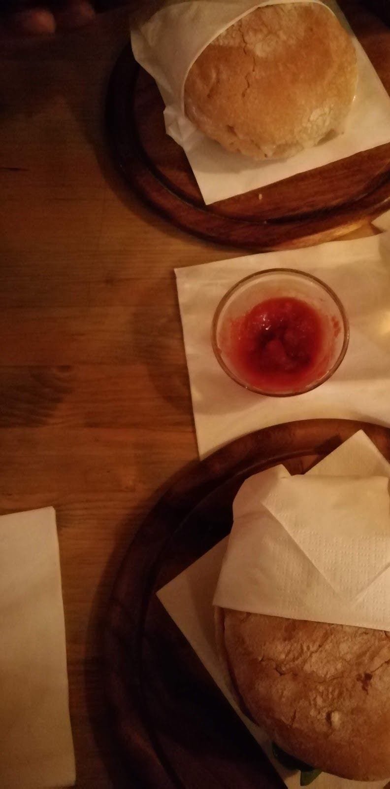 Due panini nella carta sui taglieri di legno, con una ciotolina di salsa