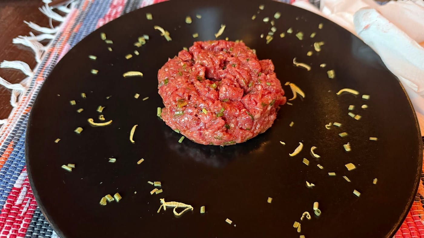Una tartare di manzo con scorza ed erba cipollina su un piatto nero
