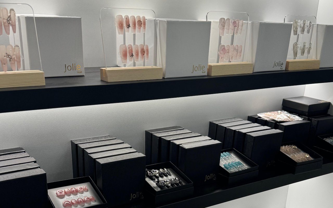 Scaffali neri con i cofanetti e gli espositori Jolie Nail