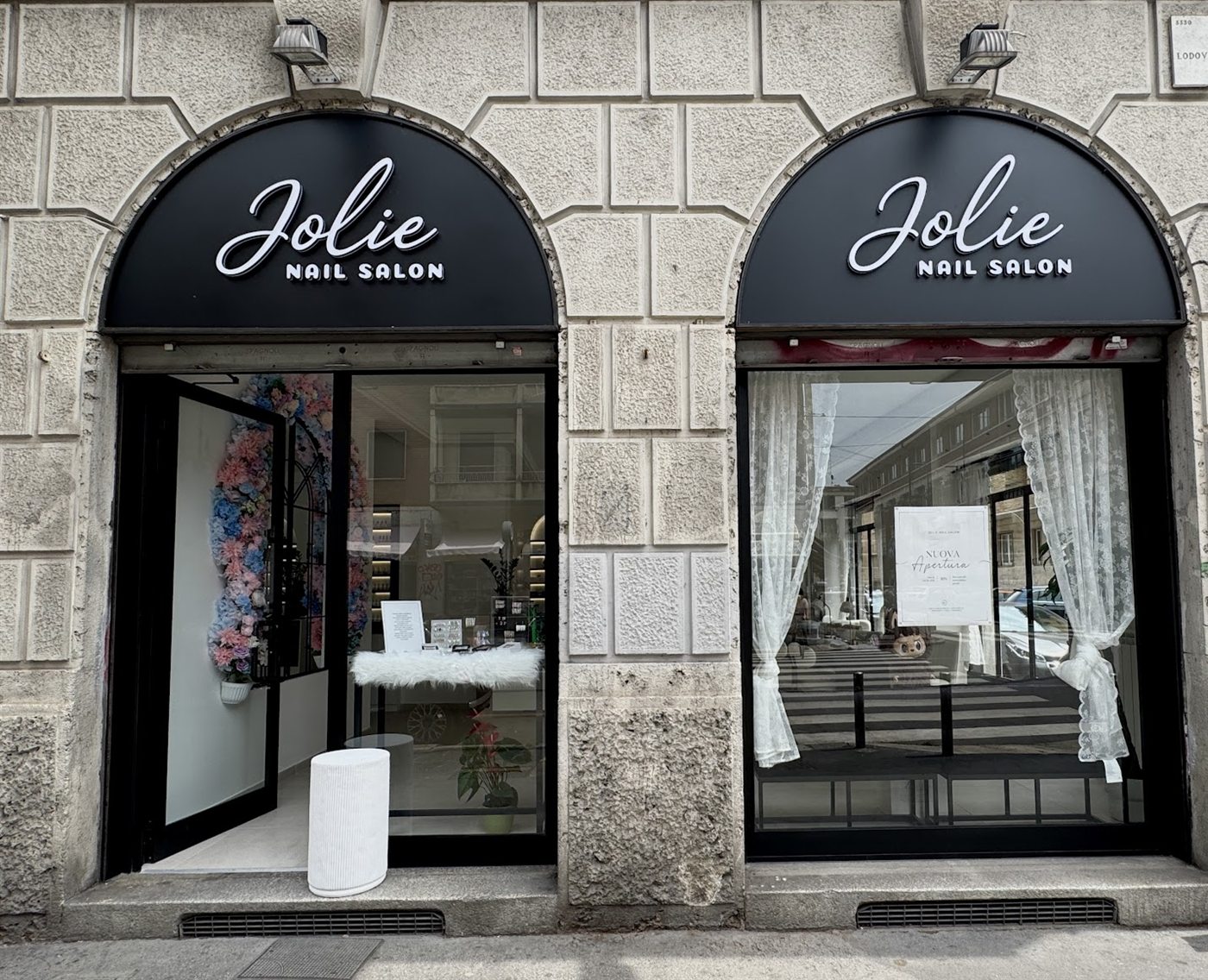 La doppia vetrina di Jolie Nail Salon in via Lodovico Montegani, con le insegne nere ad arco