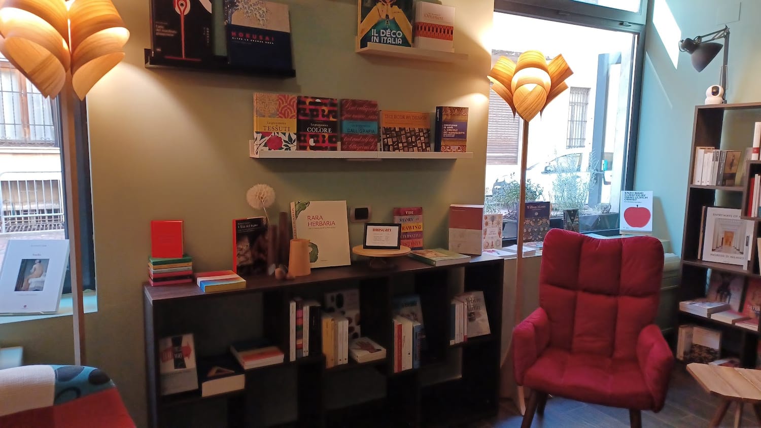 La stanza della libreria: pareti verde salvia e libri d'arte esposti come opere