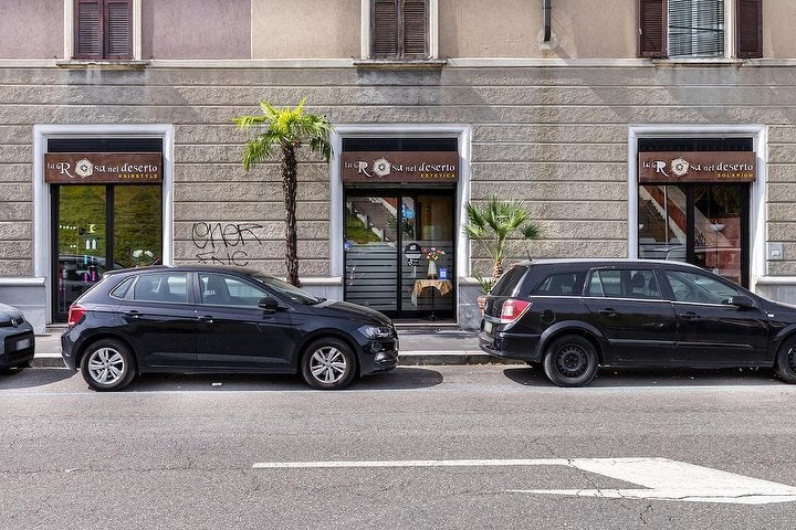 Le tre vetrine affiancate de La Rosa nel Deserto in viale Sarca, con le insegne hairstyle, estetica e solarium e due palme davanti