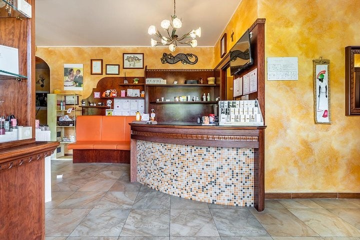 La reception dell'istituto: pareti giallo-arancio, bancone curvo a mosaico e panca in pelle arancione