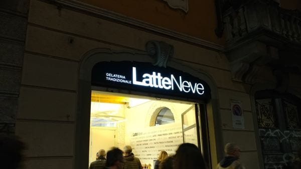 L’insegna LatteNeve accesa la sera, su via Vigevano