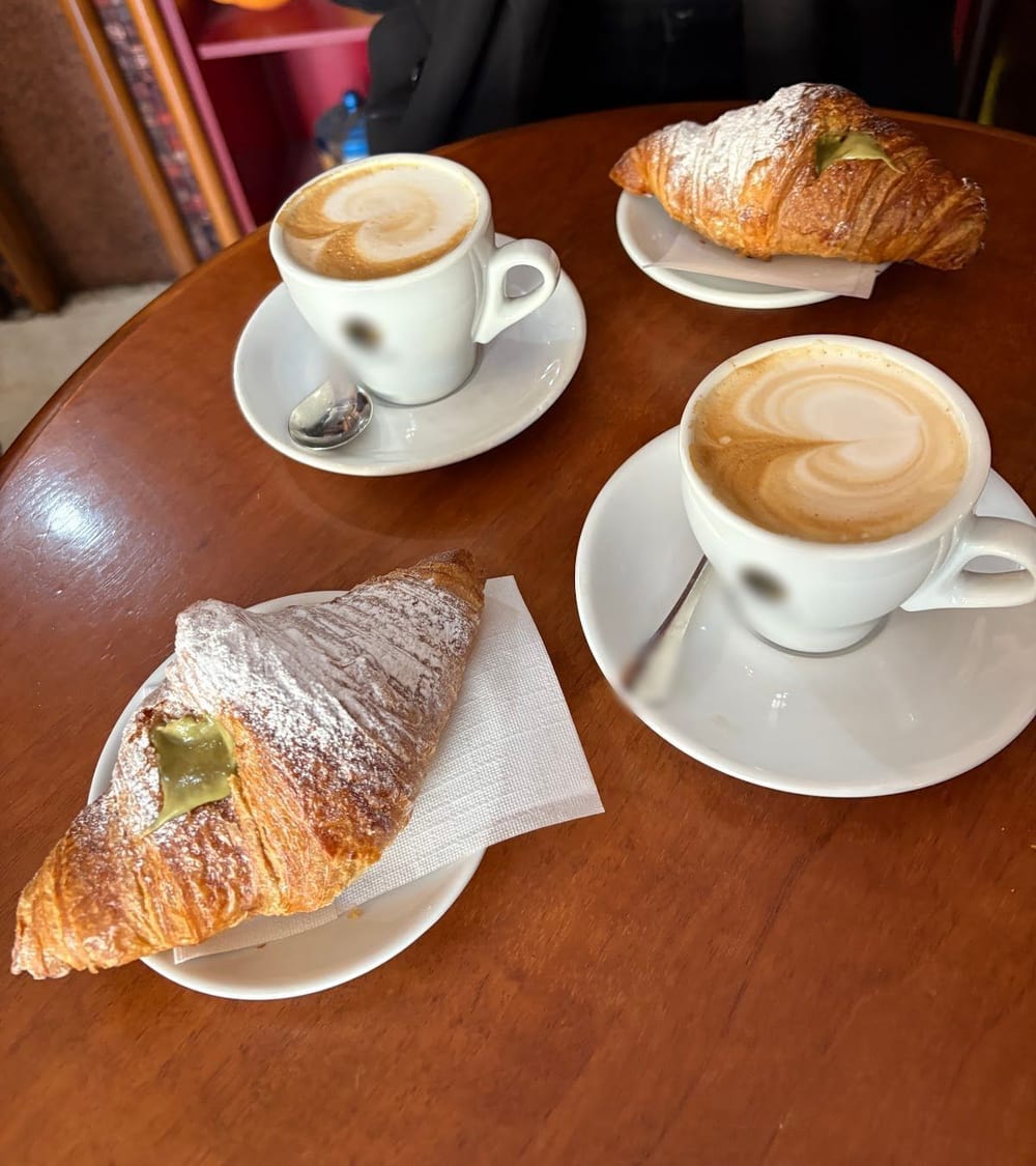 Due cappuccini col cuore e due brioche al pistacchio sul tavolino di legno