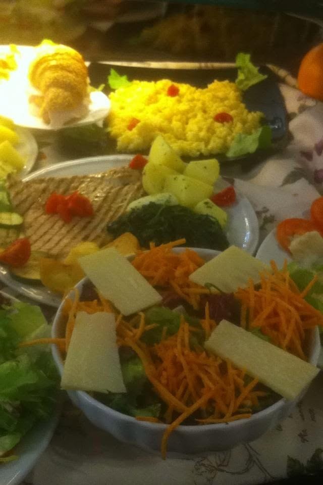 Piatti del pranzo sul banco: insalata con carote e scaglie di formaggio, riso giallo, patate, spinaci, un toast