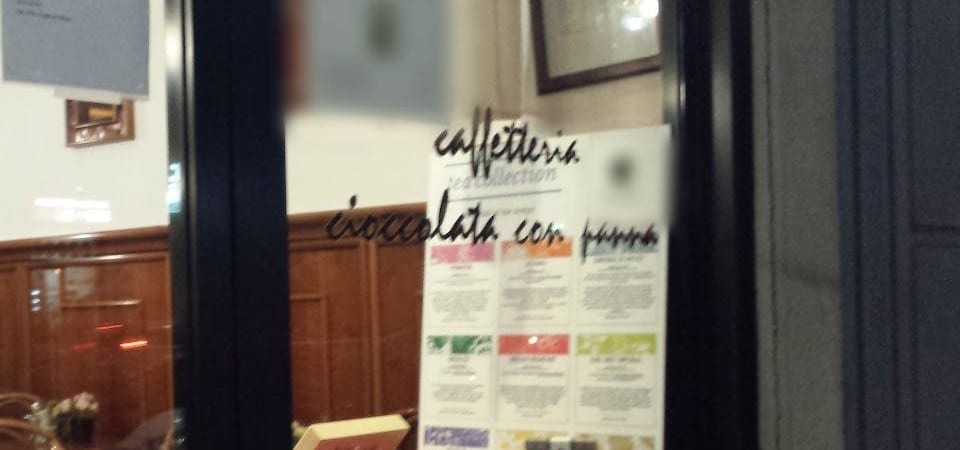 La vetrina con le scritte «caffetteria» e «cioccolata con panna», dietro la boiserie della sala
