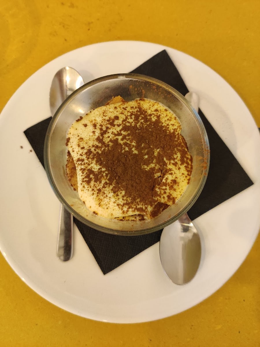 Il tiramisù della casa con due cucchiaini, sul tavolo giallo