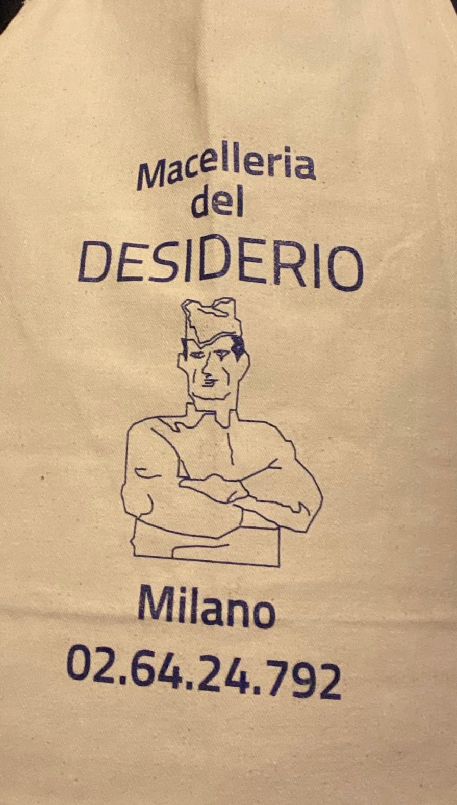 Il grembiule della macelleria: Macelleria del Desiderio, Milano, il telefono, e il macellaio disegnato a braccia conserte