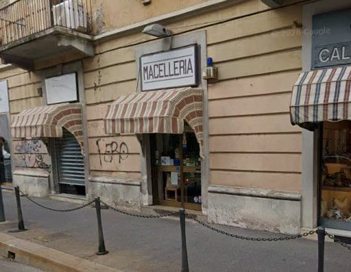 L'insegna Macelleria e la tenda a righe su via Luigi Ornato, viste dalla strada