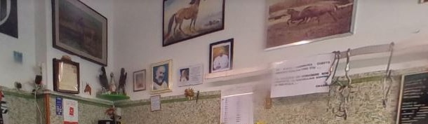 La parete sopra il banco, con i quadri di cavalli appesi