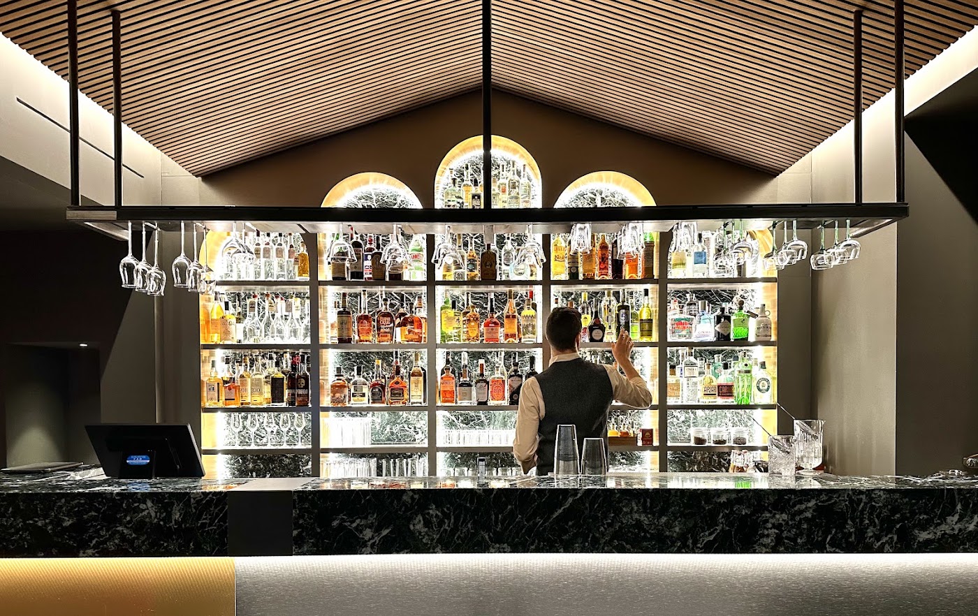 Il cocktail bar in marmo di Manna, bottiglie retroilluminate, illuminato di sera