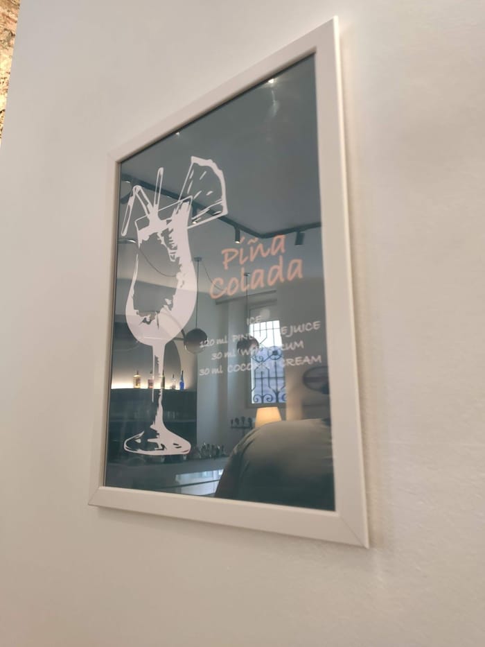 Un'altra stampa appesa in sala: il disegno bianco di una Piña Colada su fondo verde scuro.
