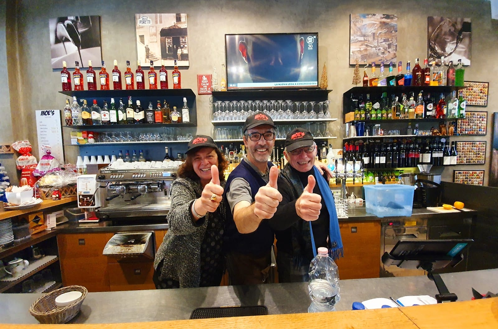 Il banco bar di Moe's: tre persone dello staff col cappellino Moe's Milano, la macchina espresso e le bottiglie alle spalle