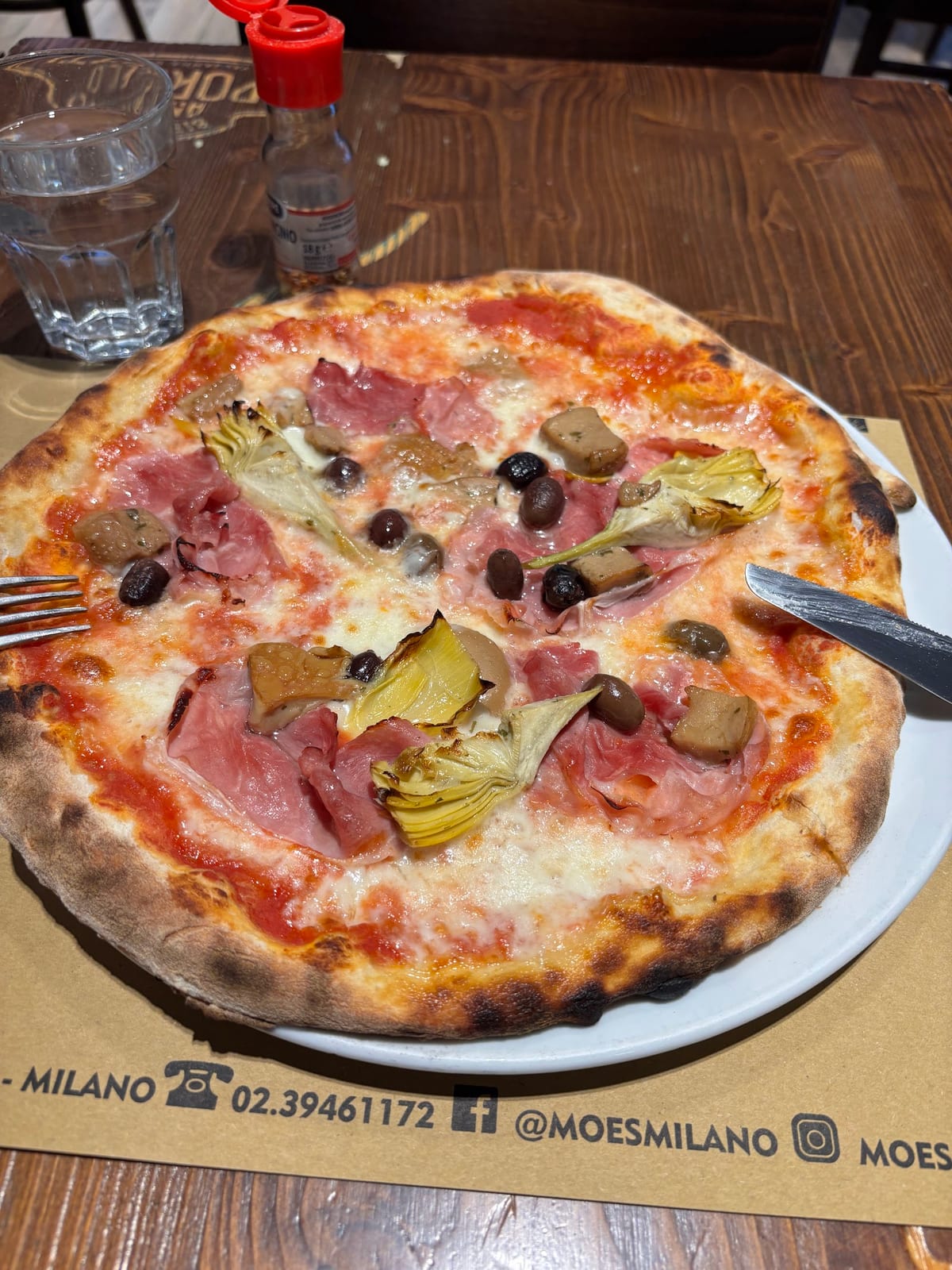 Pizza con prosciutto, carciofi e olive sulla tovaglietta Moe's